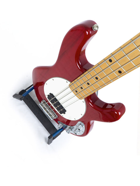 Red Music Man Stingray 4 H Bass guitar on a stand, set against a bright white background.