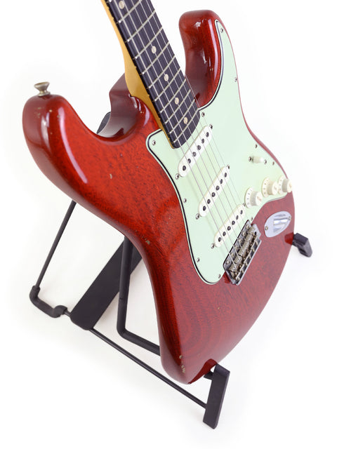 Red electric guitar on a black stand, featuring the 2019 Fender Custom Shop Jason Smith Masterbuilt Stratocaster.
