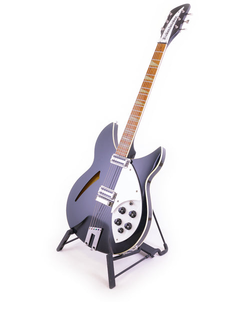 Rickenbacker 360 WB guitar, black and sleek, resting on a stand with a bright white backdrop.
