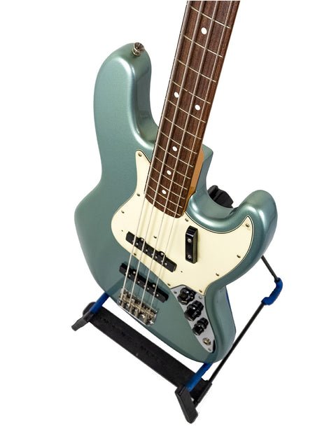 Seafoam green electric guitar with a white pickguard on a stand, isolated on white background.