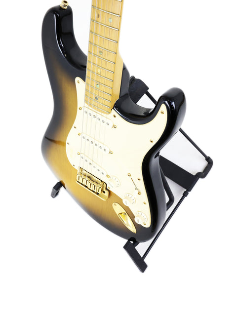 Sunburst electric guitar with maple fretboard on a stand, isolated on white background.