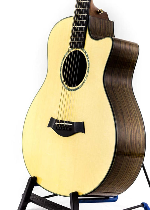 Taylor Custom GS Baritone 6 guitar elegantly positioned on a stand, with a plain white background.