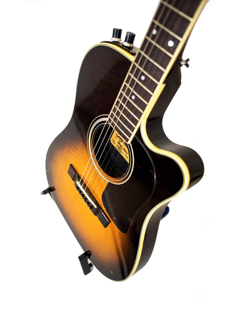 The 1984 Washburn Mirage Deluxe guitar stands proudly on a stand, highlighted by a simple white background.
