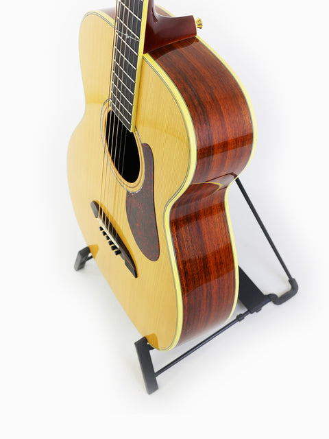 The Alvarez Yairi FYM95V guitar rests on a stand, highlighted by a pristine white background, emphasizing its craftsmanship.