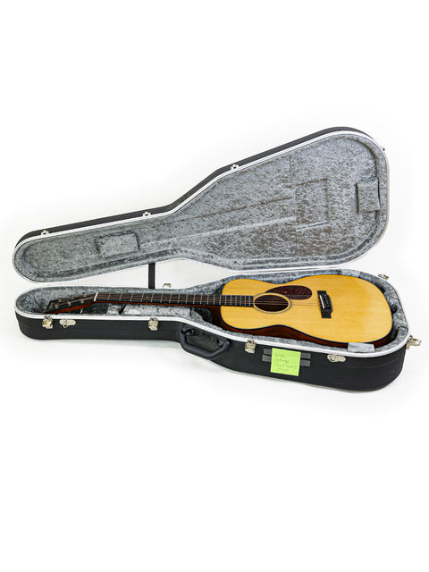 The Collings Julian Lage Signature OM1 guitar rests in its case, highlighted by a pristine white background for a striking visual.

