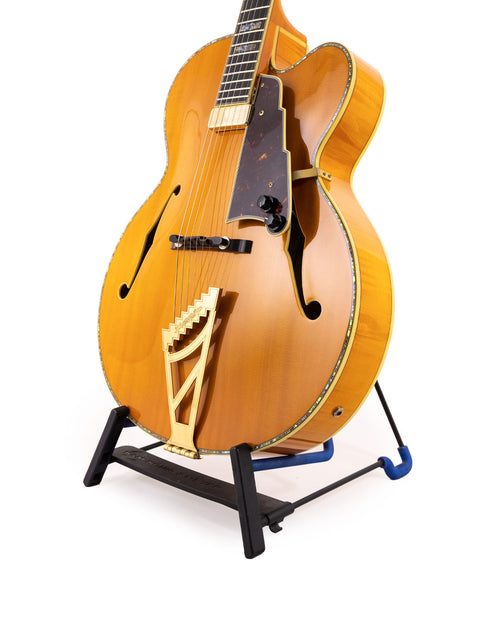The D’Angelico New Yorker Series Excel EXL-1DP guitar rests on a stand, highlighted by a pristine white backdrop.