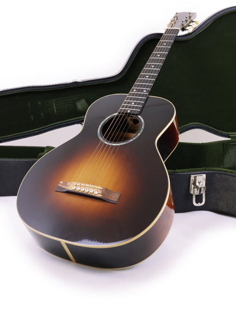 The image features a Beau Hannam Parlour guitar, crafted in Australia in 2009, nestled securely in its protective case.