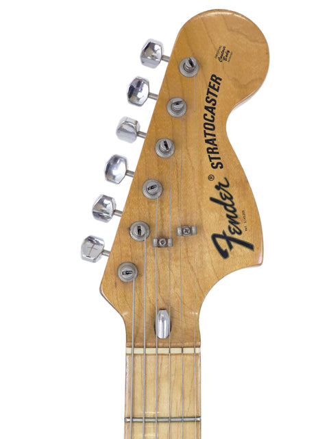 The image features a vintage 1954 Fender Stratocaster, highlighting its iconic shape and historical significance.