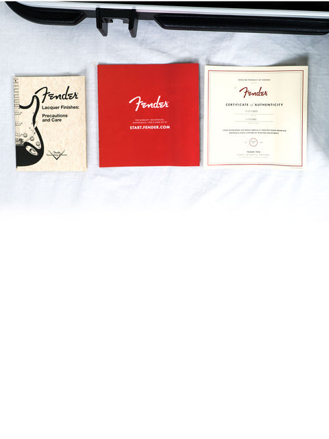 Three Fender guitar booklets on a white surface—one beige, one red, one white with text.