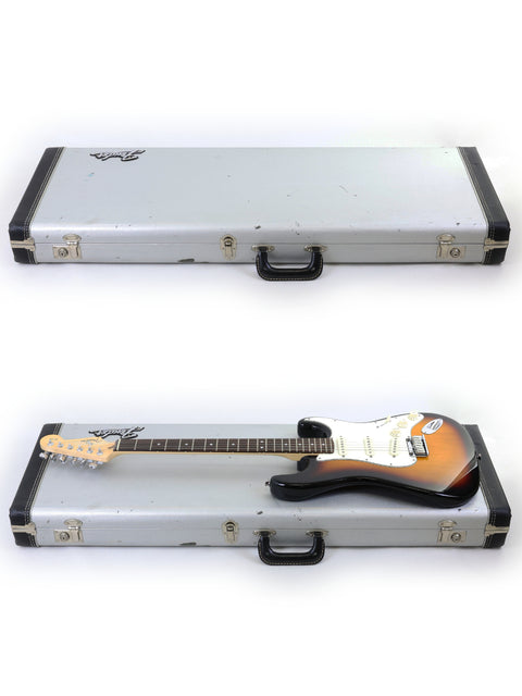 Two guitars, including a 2006 Fender 60th Anniversary American Stratocaster, are displayed in a case against a white backdrop.