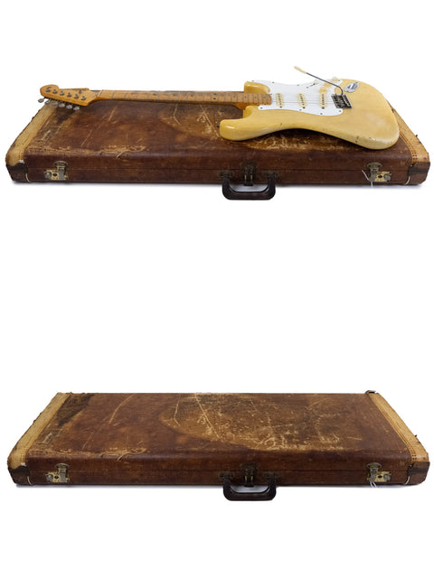Two old guitar cases display a 1959 USA Fender Stratocaster, featuring a blond body and maple neck.
