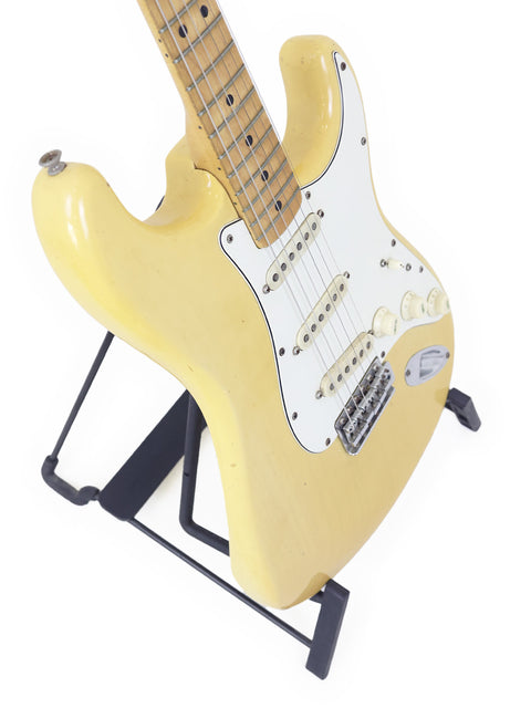 Vintage 1954 Fender Stratocaster electric guitar in yellow, artistically placed on a stand, showcasing its iconic style.