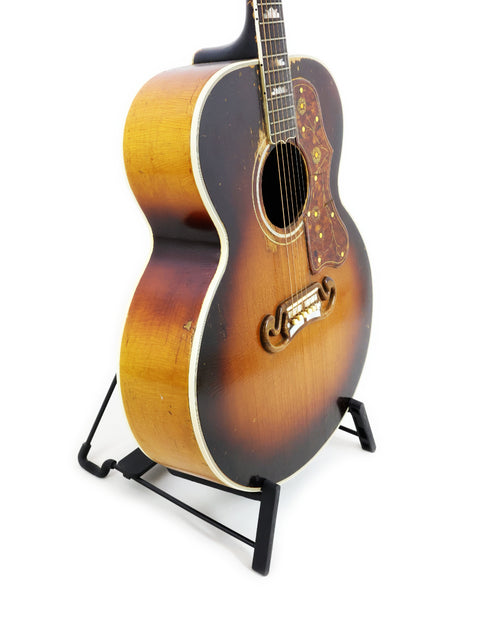 Vintage 1954 Gibson J-200 acoustic guitar on a stand, featuring its iconic design and rich wood finish.