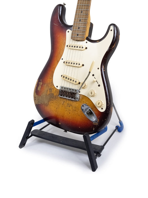 Vintage 1958 Fender Stratocaster guitar elegantly positioned on a stand with a bright white background.