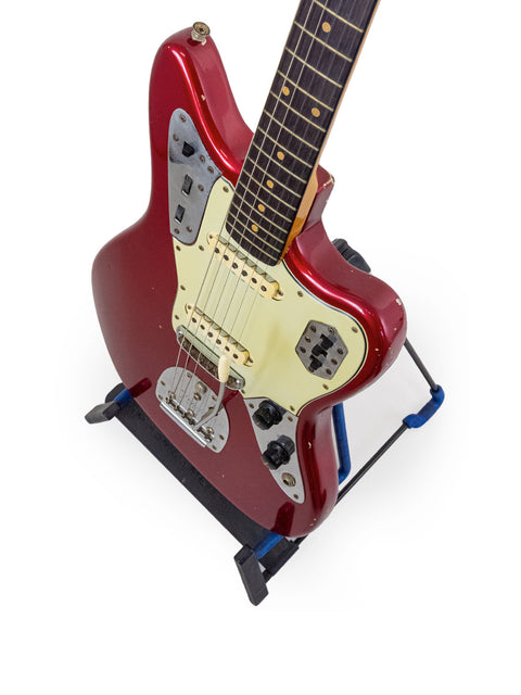 Vintage 1964 Fender Jaguar in Candy Apple Red resting on a blue stand.