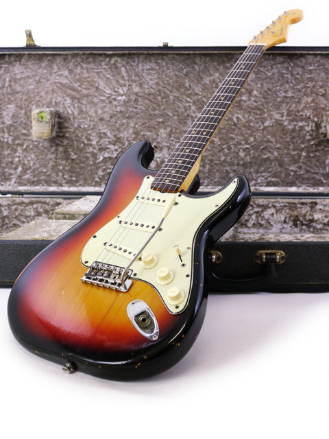 Vintage 1964 Fender Stratocaster guitar nestled in its case, featuring a stylish refinish and iconic design.