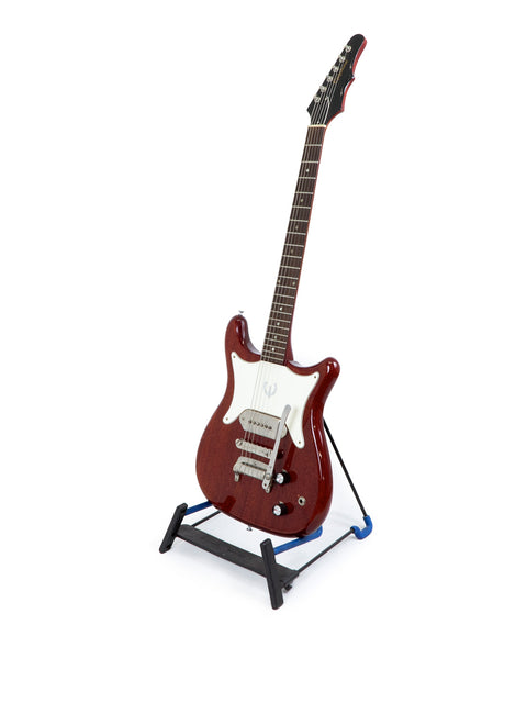 Vintage 1965 red Epiphone Coronet guitar on a stand with a blue base, highlighting its classic design and vibrant color.