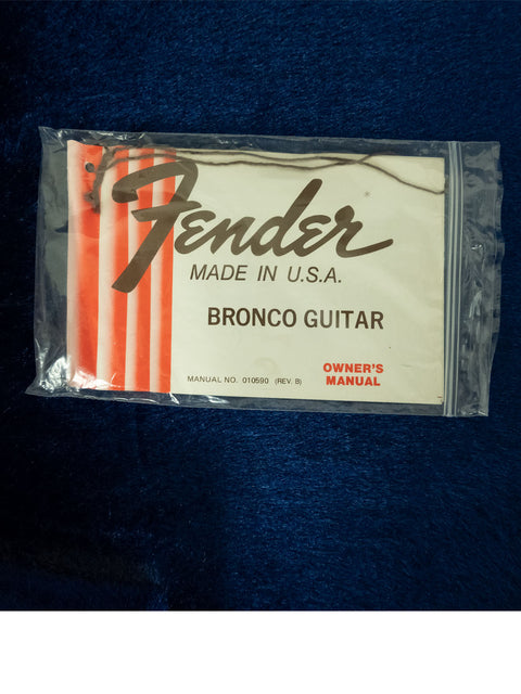 Vintage 1976 Fender Bronco electric guitar displayed in a plastic bag, showcasing its classic design and condition.