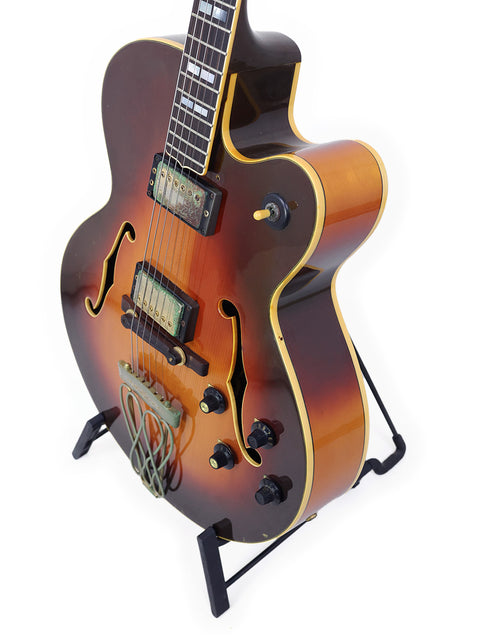 Vintage 1982 Yamaha AE1200 guitar with a stunning sunburst finish, proudly resting on a stand, ready to play.
