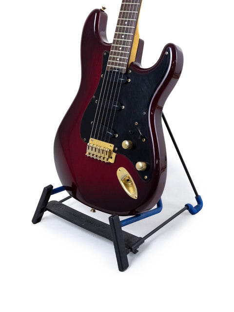 Vintage 1989 Levinson Blade R2 Strat-style guitar in red, elegantly positioned on a black base stand.