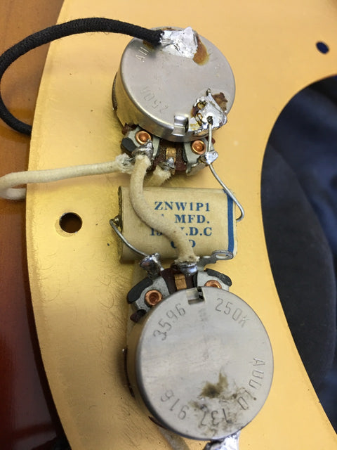 Vintage Fender Precision Bass guitar (1958/59) with a pickup and wire, highlighting its iconic features and style.
