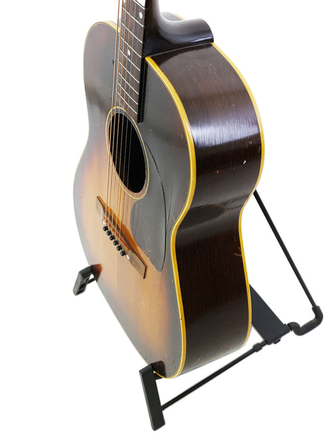 Vintage Gibson LG-2 guitar from 1954 positioned on a stand, emphasizing its timeless style and quality.