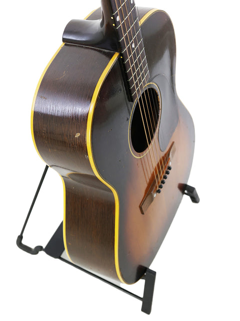 Vintage Gibson LG-2 guitar from 1954 resting on a stand, featuring a rich wooden body and timeless appeal.