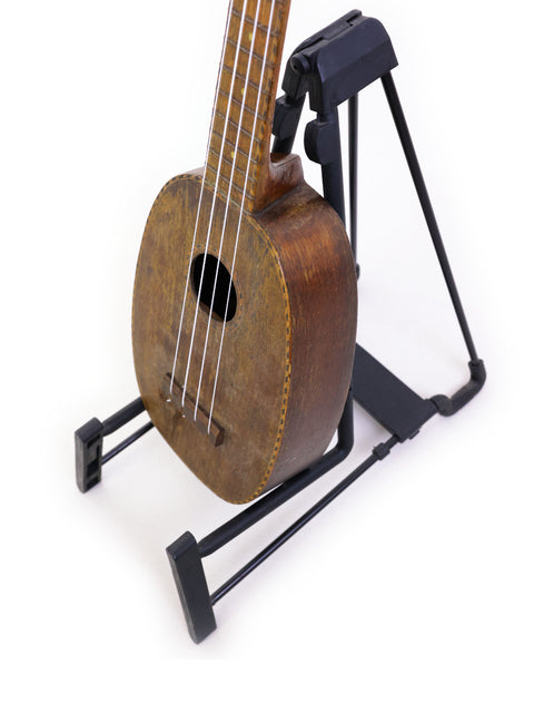 Vintage Kamaka Pineapple Ukulele from 1930 resting on a black stand, emphasizing its unique Hawaiian craftsmanship.