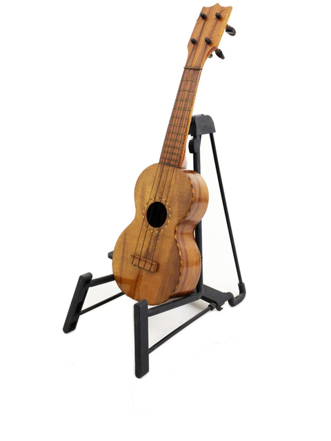 Vintage Royal Style 3 Koa Ukulele from Hawaii (c. 1916) displayed on a black stand, highlighting its craftsmanship.

