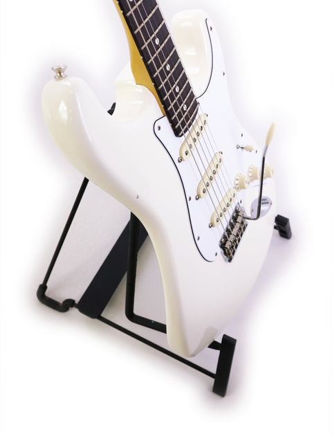 White electric guitar on a black stand with a white background.