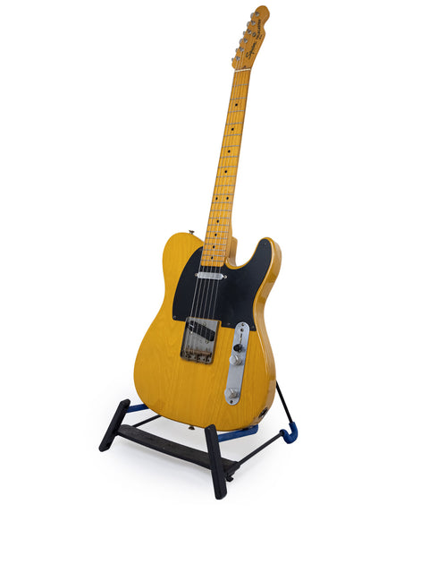 Yellow Fender Squier JV Telecaster guitar displayed on a black base stand, highlighting its classic 1984 reissue style.