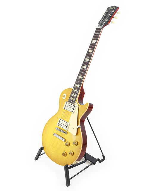 Yellow Gibson Custom Shop '58 Les Paul Standard R/I guitar displayed on a stand with a clean white backdrop.