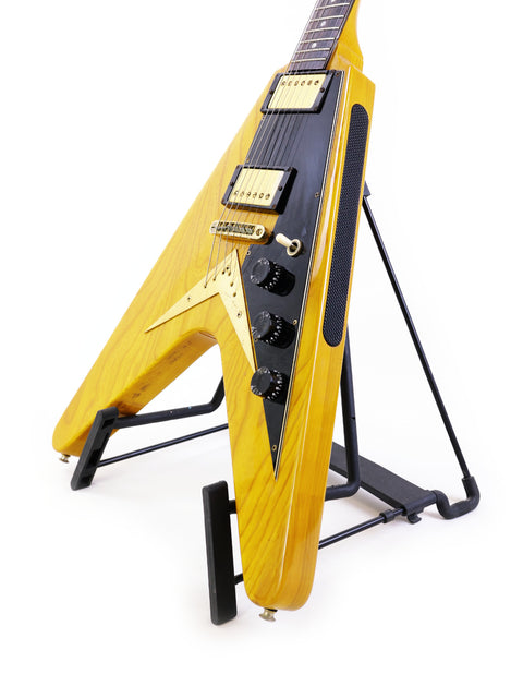 Yellow Ibanez 2387CT Rocket Roll Sr. Flying V guitar displayed on a stand, equipped with a black strap, from Japan, 1976-77.