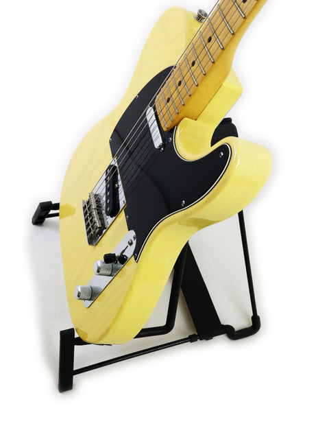 Yellow electric guitar on a stand against a white background.