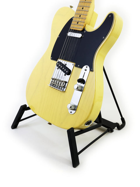 Yellow electric guitar on a stand against a white background.