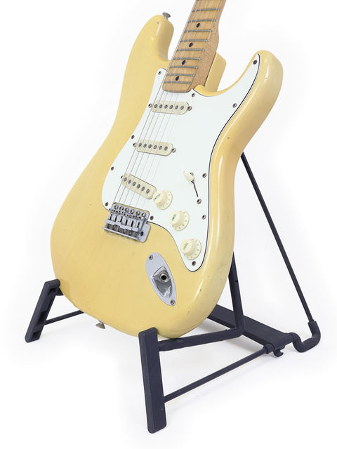 Yellow vintage Fender Stratocaster guitar from 1954, showcased on a stand, highlighting its classic design.