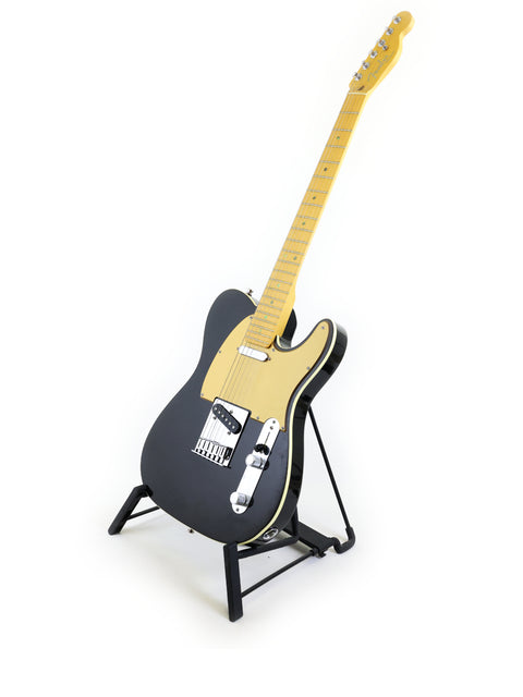 black and gold Fender American Deluxe Telecaster guitar displayed elegantly on a stand.