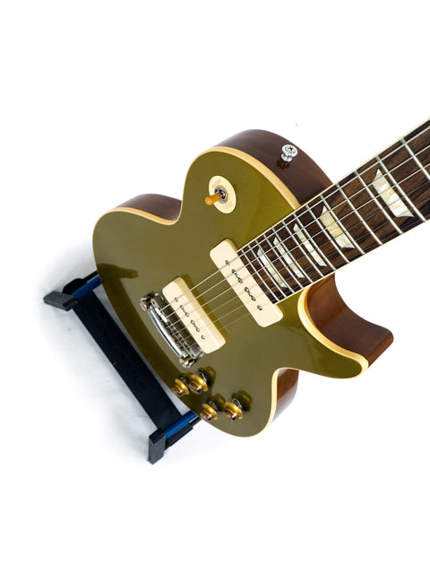 green electric guitar on a black stand, showcasing the Gibson Custom Historic Limited Edition VOS LPR-6 1956 Les Paul Reissue.