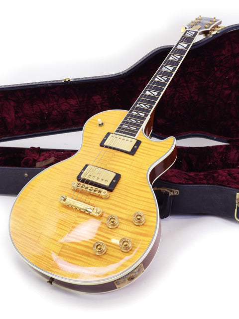vibrant yellow electric guitar, the Gibson Les Paul Supreme 2003, displayed in its sturdy case.