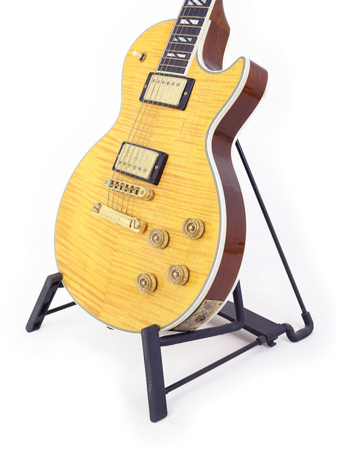 vibrant yellow electric guitar, the Gibson Les Paul Supreme from 2003, elegantly positioned on a stand for display.