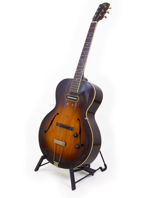 vintage 1938 Gibson ES-150 guitar displayed on a stand against a clean white background.