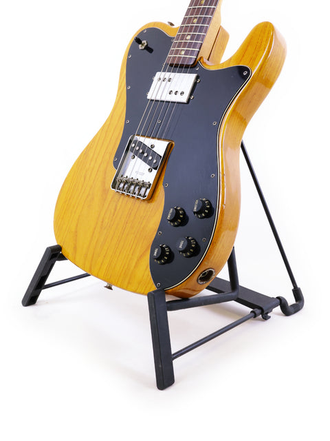 vintage 1977 Fender Telecaster Custom guitar resting on a stand, set against a stark white backdrop.